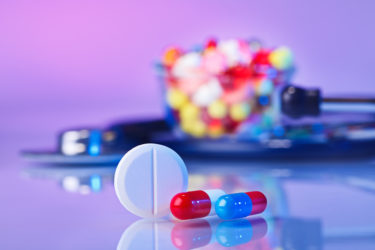 Pills and tablets macro still life on violet, medical therapeutic concept