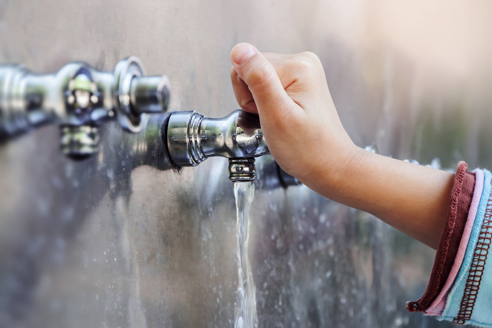 Child's hand with drinking water running from tap water